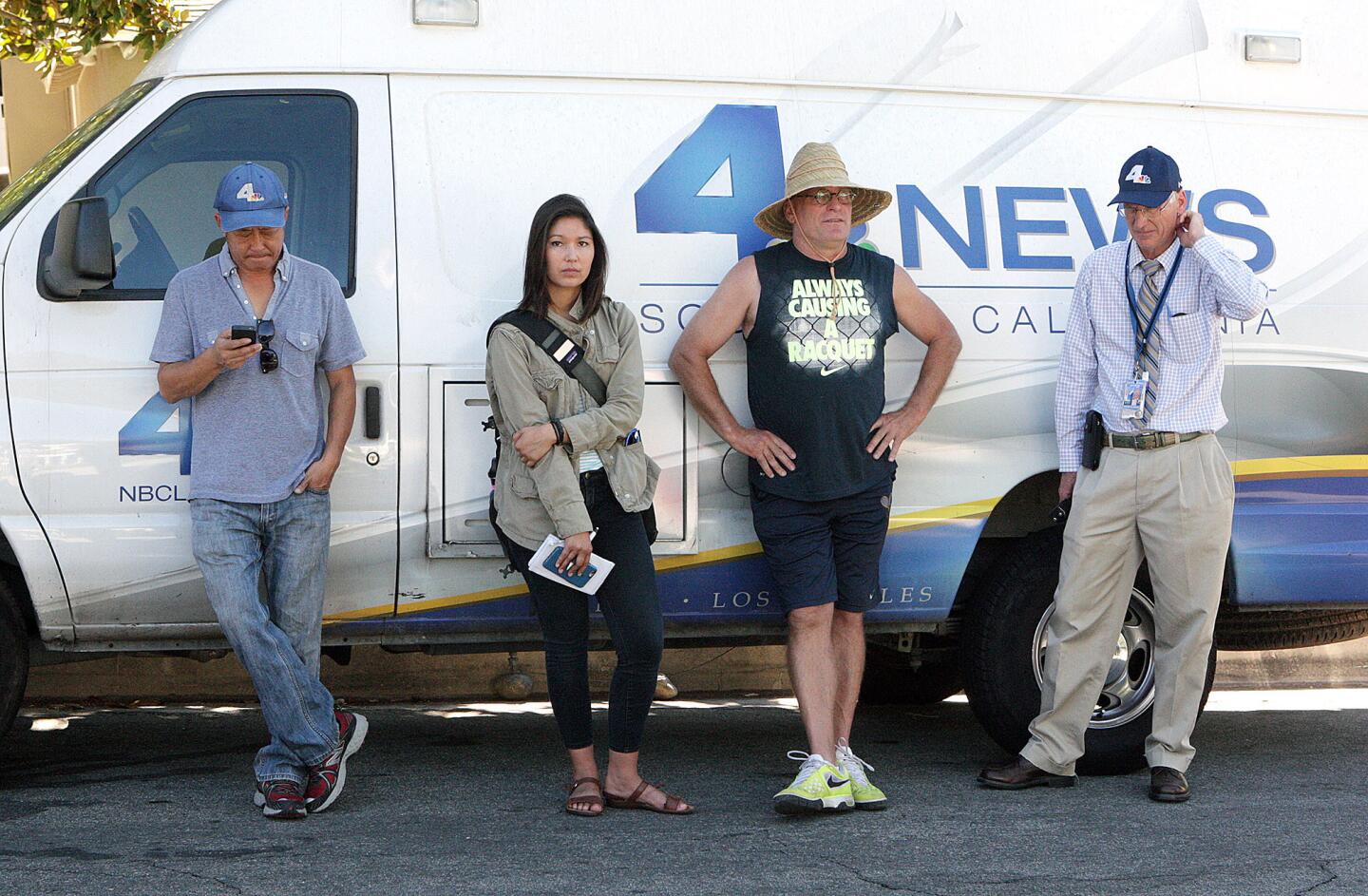 Reporters and TV news crew members stand in the shade for long day at the scene of a murder-suicide on the 5000 block of Crown Avenue in La Cañada Flintridge on Monday, Sept. 7, 2015. On Sunday night, a 5-year veteran of the Los Angeles County Fire Department shot and killed his wife, a 2-year veteran of the Sheriff's Department. He then killed himself at a county Fire Department facility in Pacoima, according to officials.