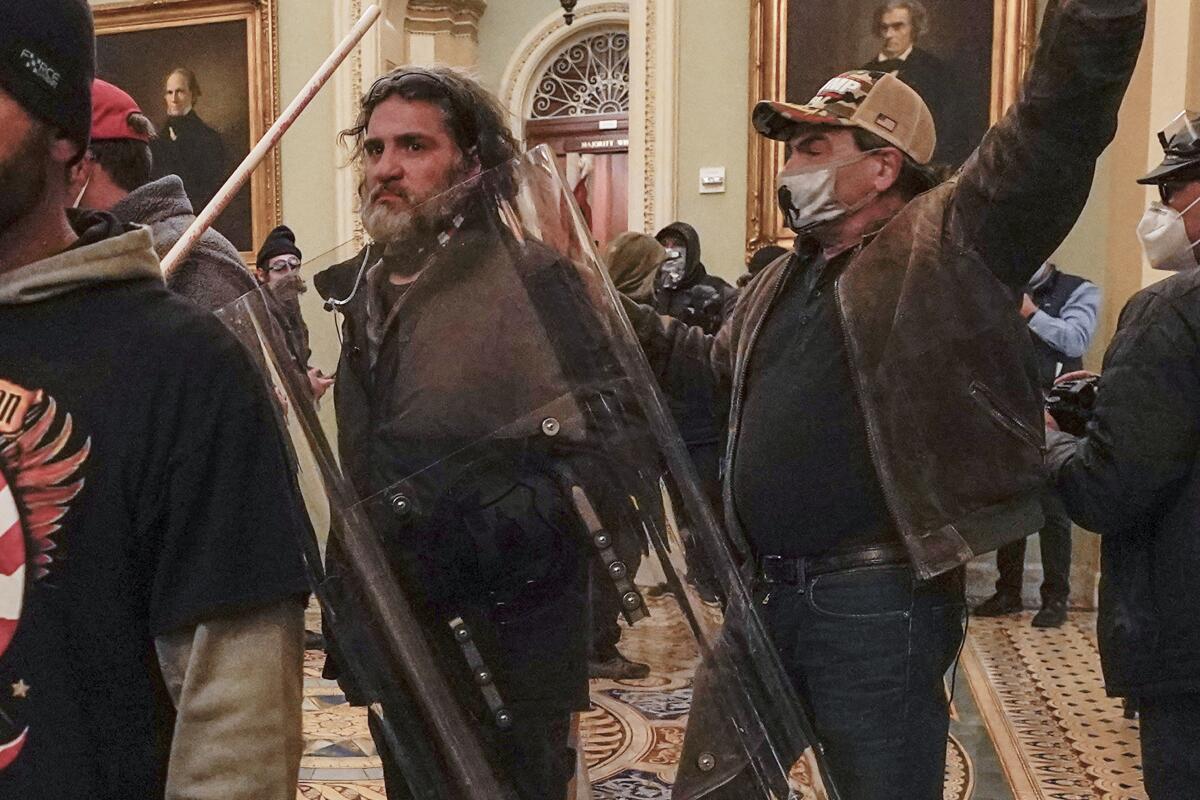 Several rioters, including one holding a police shield, inside the U.S. Capitol.