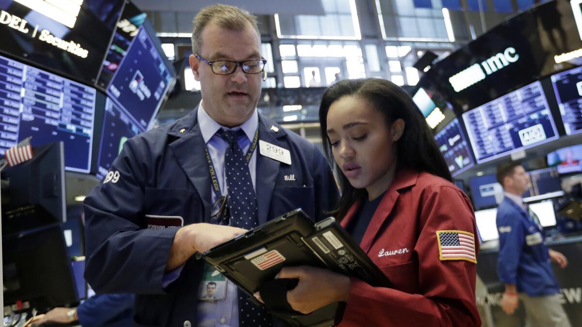 Traders William Lawrence and Lauren Simmons work on the floor of the New York Stock Exchange.