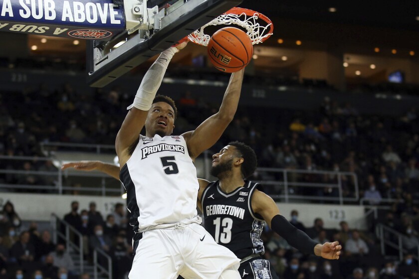 Providence's Ed Croswell (5) slam dunks past the defense of Georgetown's Donald Carey (13) during the first half of an NCAA college basketball game Thursday, Jan. 20, 2022, in Providence, R.I. (AP Photo/Stew Milne)