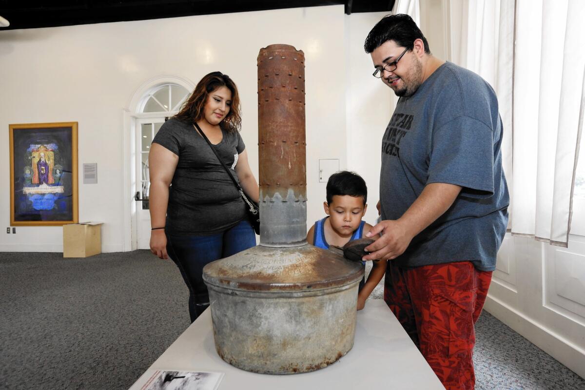 Stephanie Romero, her son Ricky, 5, and fiancee David Souza look at a smudge pot at the exhibit at Pico House.