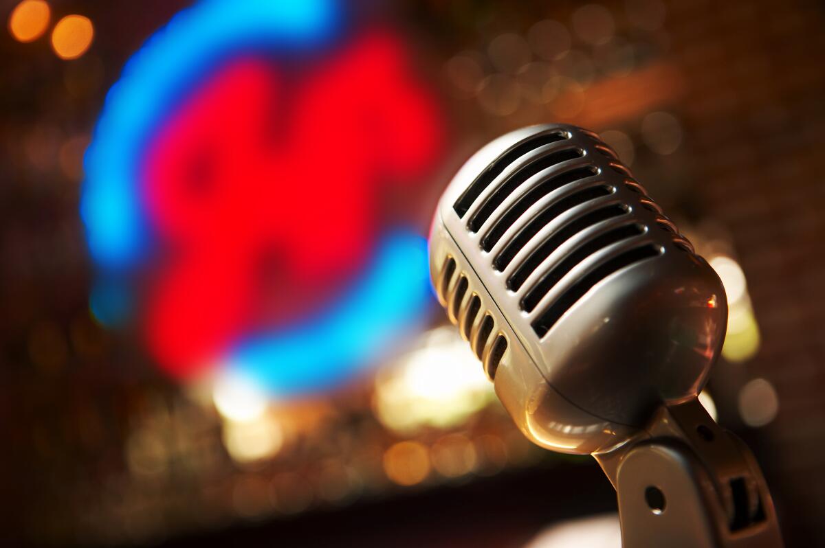 An old-fashioned microphone with an out-of-focus neon sign in the background