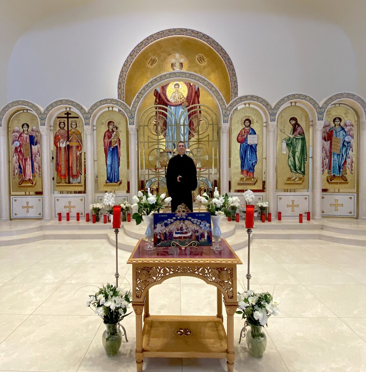 Father Michael Sitaras in the chapel, with some of the mosaic saints.