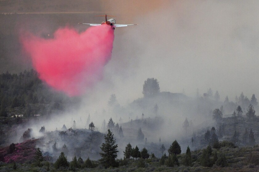 A cloud of pink descends from an aircraft over gray smoke.
