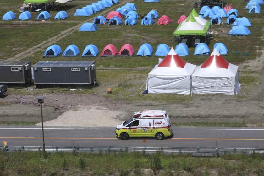 An ambulance passes a scout camping site during the World Scout Jamboree in Buan, South Korea, Wednesday, Aug. 2, 2023. Dozens of people were treated for heat-related illnesses at the World Scout Jamboree being held in South Korea, which is having one of its hottest summers in years. (Jeonbuk Fire Station/Yonhap via AP)