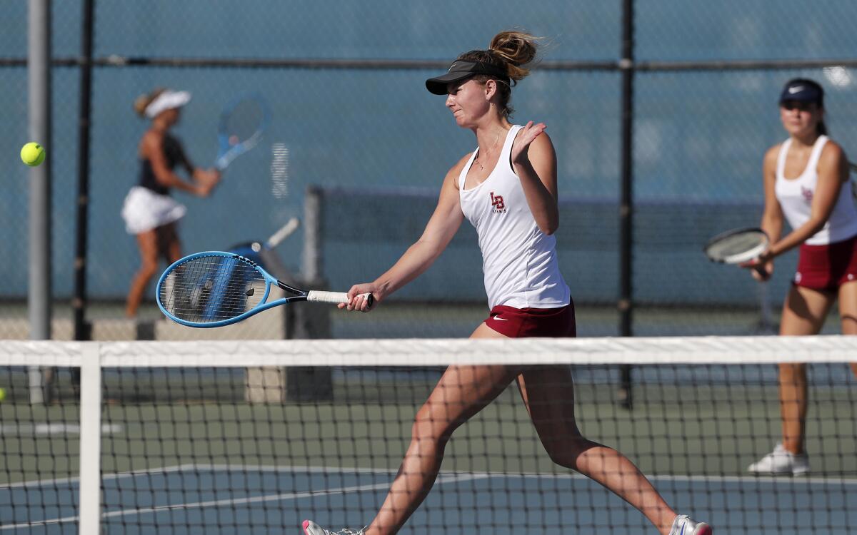 Laguna Beach's Ella Pachl, center, and partner Natty Cenan, right, compete during a No. 1 doubles set in a Sunset Conference crossover match at Newport Harbor on Tuesday.