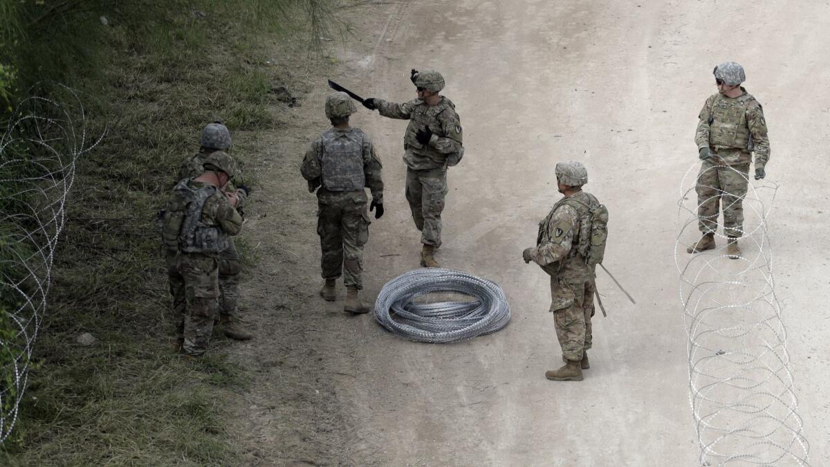 Members of the U.S.military place razor wire along the U.S.-Mexico border near the McAllen-Hidalgo International Bridge on Friday in McAllen, Texas.