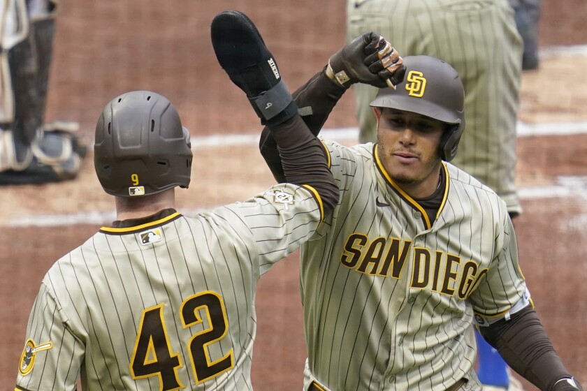 San Diego Padres' Manny Machado, right, is greeted by a teammate after hitting a two-run home run against the Pittsburgh Pirates during the first inning of a baseball game, Thursday, April 15, 2021, in Pittsburgh. (AP Photo/Keith Srakocic)