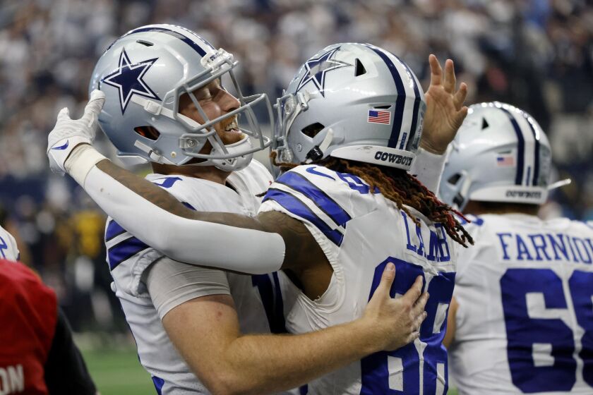Dallas Cowboys quarterback Cooper Rush, left, and wide receiver CeeDee Lamb (88) celebrate after Rush threw a touchdown pass to Lamb in the second half of a NFL football game against the Washington Commanders in Arlington, Texas, Sunday, Oct. 2, 2022. (AP Photo/Ron Jenkins)