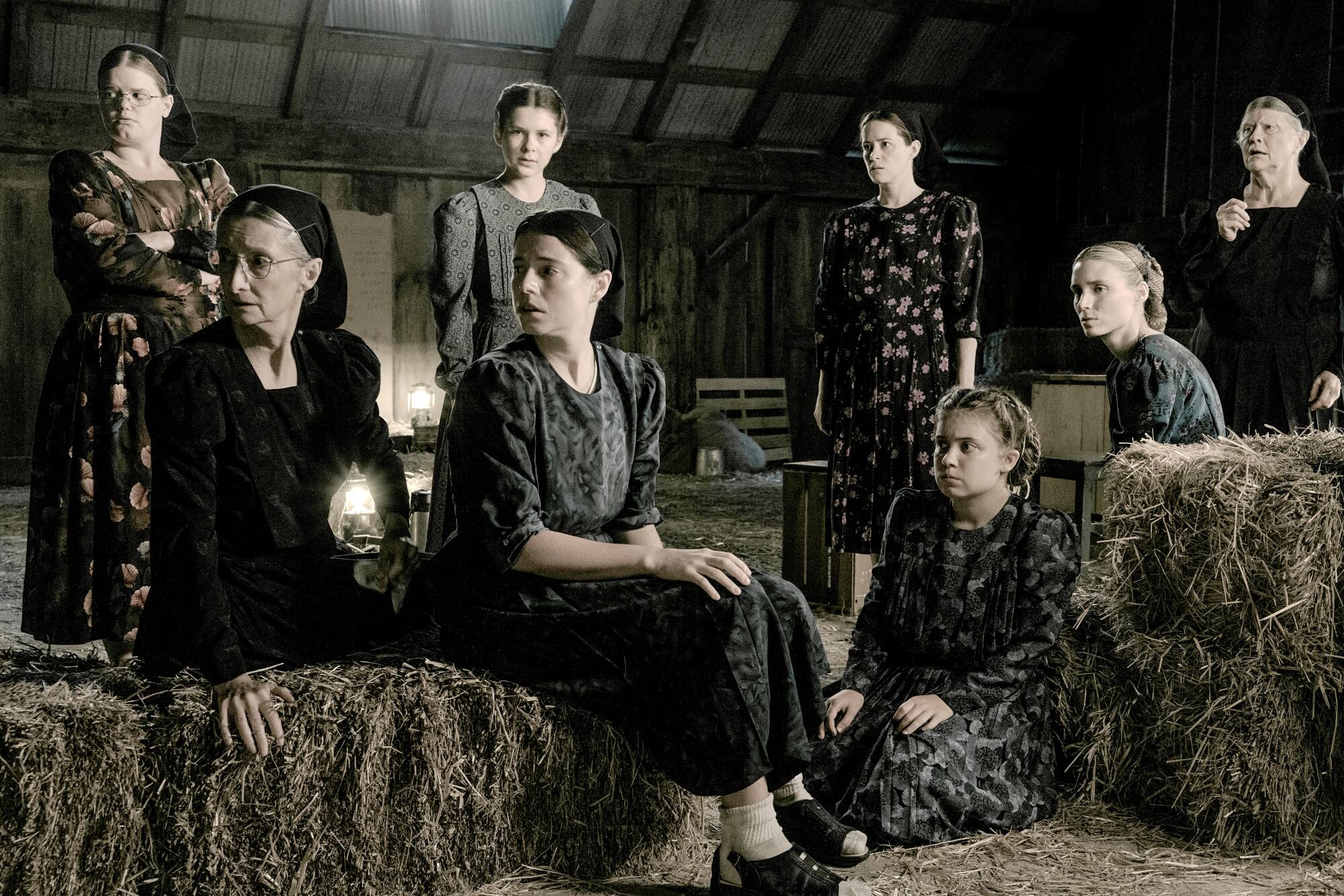 A group of conservatively dressed women and girls sit in a hayloft in a scene from "Women Talking."
