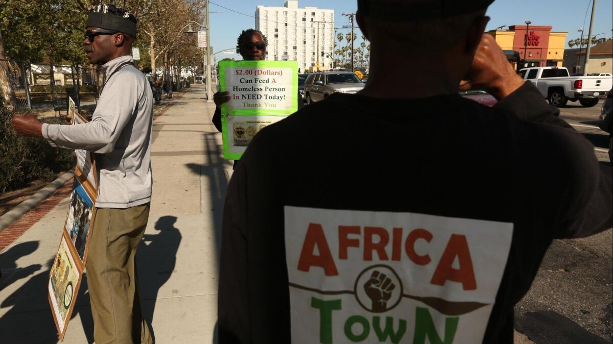 Kevin Wharton Price, left, founder of the Africa Town Coalition, and fellow members Abron Farley Jr. and William "Billion" Campbell shout to drivers and pedestrians to consider renaming Leimert Park "Africa Town."