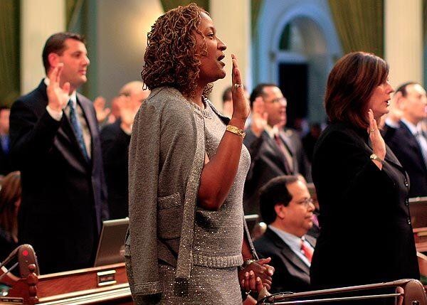 Freshman Assemblywoman Holly Mitchell, a Democrat from Los Angeles, holds her son Ryan's hand as she is sworn in with other new legislators at the Capitol in Sacramento. She represents the 47th District. See full story