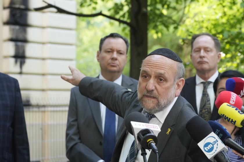 Poland's chief rabbi Michael Schudrich points to the Nożyk Synagogue in Warsaw, Poland, on Wednesday, May 1, 2024. The synagogue was damaged in a attack with Molotov cocktails overnight. (AP Photo/Czarek Sokolowski)