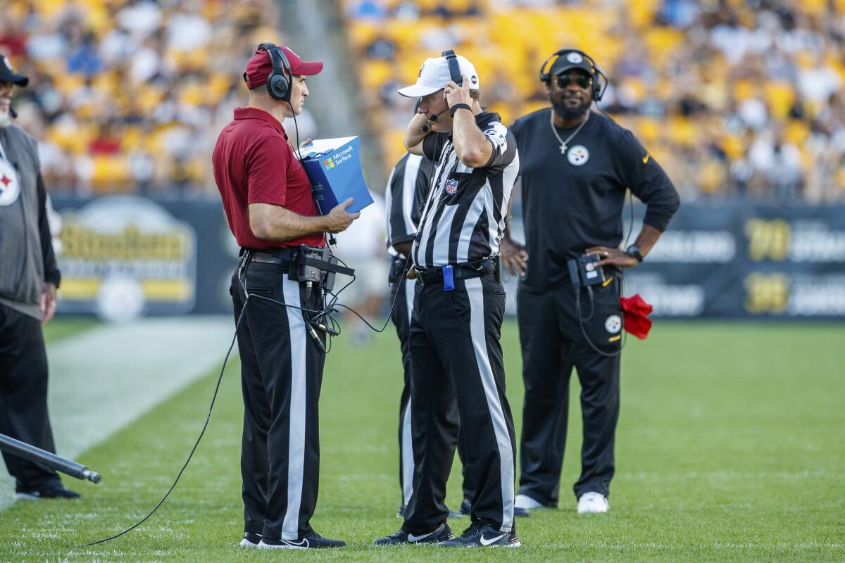 Referee Alex Kemp watches instant replay in front of Pittsburgh Steelers coach Mike Tomlin.