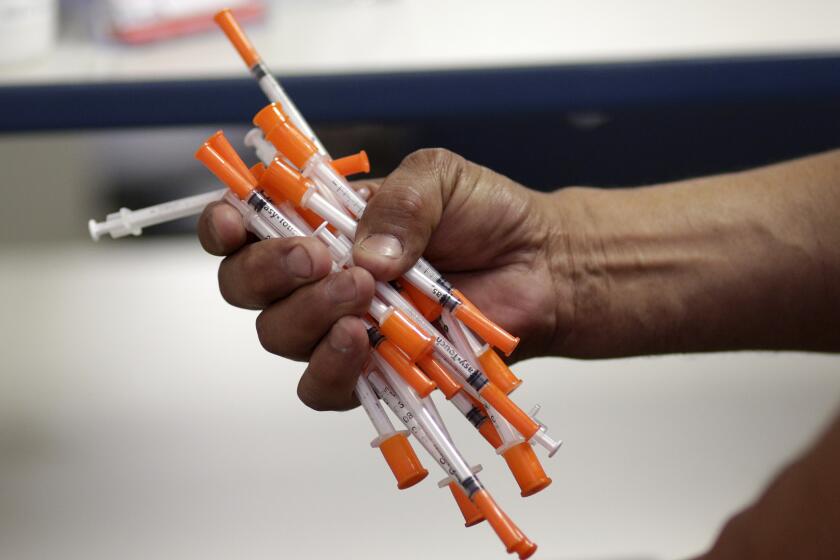 In this Monday, May 6, 2019 photo, Jose Garcia, an injection drug user, deposits used needles into a container at the IDEA exchange, in Miami. The University of Miami pilot program allows users to exchange used syringes for clean ones in order to avoid the transmission of HIV, Hepatitis C and other blood-borne diseases. Needle exchanges could eventually come to other parts of the state under a new law signed by Gov. Ron DeSantis. (AP Photo/Lynne Sladky)