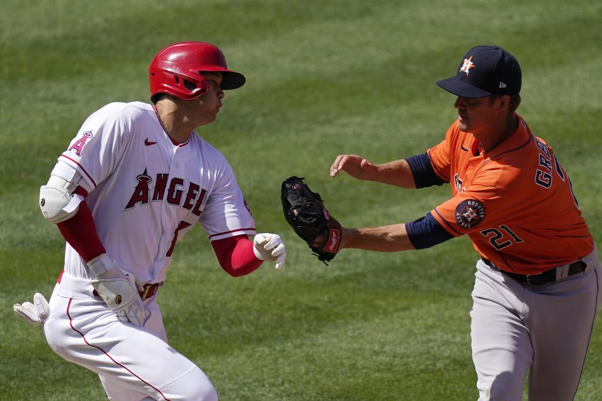 Angels' Shohei Ohtani is tagged out as he runs to first by Houston Astros pitcher Zack Greinke.