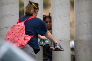 A volunteer holds out shoes for a migrant to pick out at the U.S.-Mexico border in San Diego on Sunday, May 14, 2023.