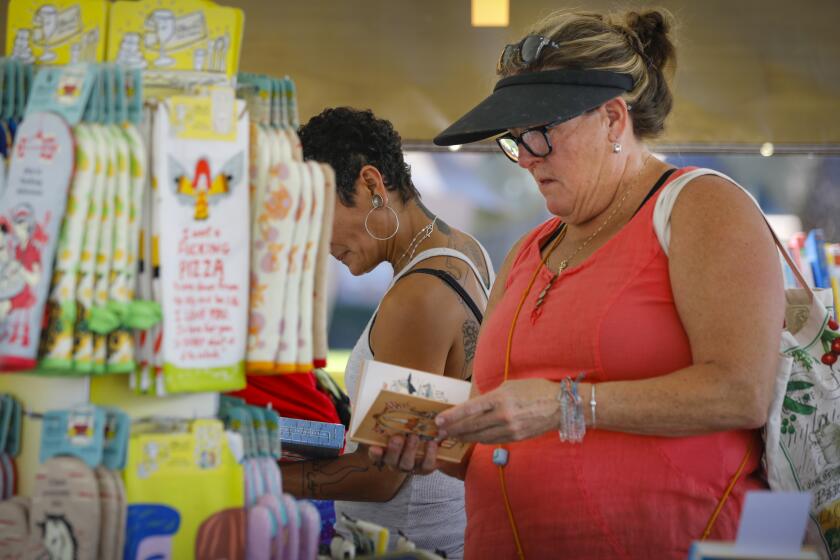Diana Drummey of La Mesa browses one of the books for sale in the Book Catapult booth during the San Diego Union-Tribune Festival of Books, at Liberty Station, August 24, 2019, in San Diego, California.