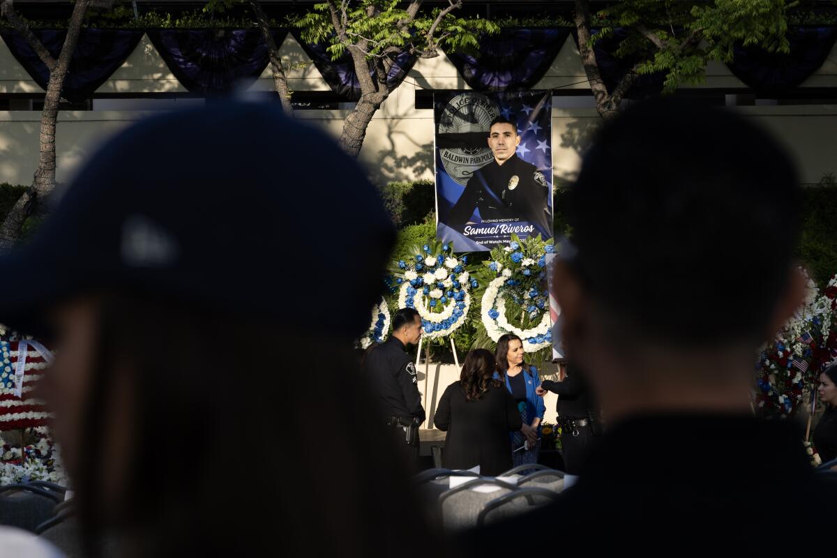 People look at photos and flowers at a vigil for Officer Samuel Riveros.