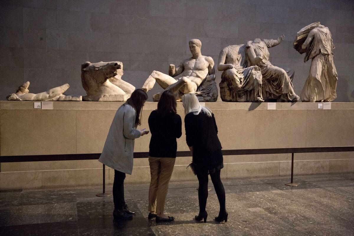  Women stand by a marble statue of a naked youth thought to represent Greek god Dionysos