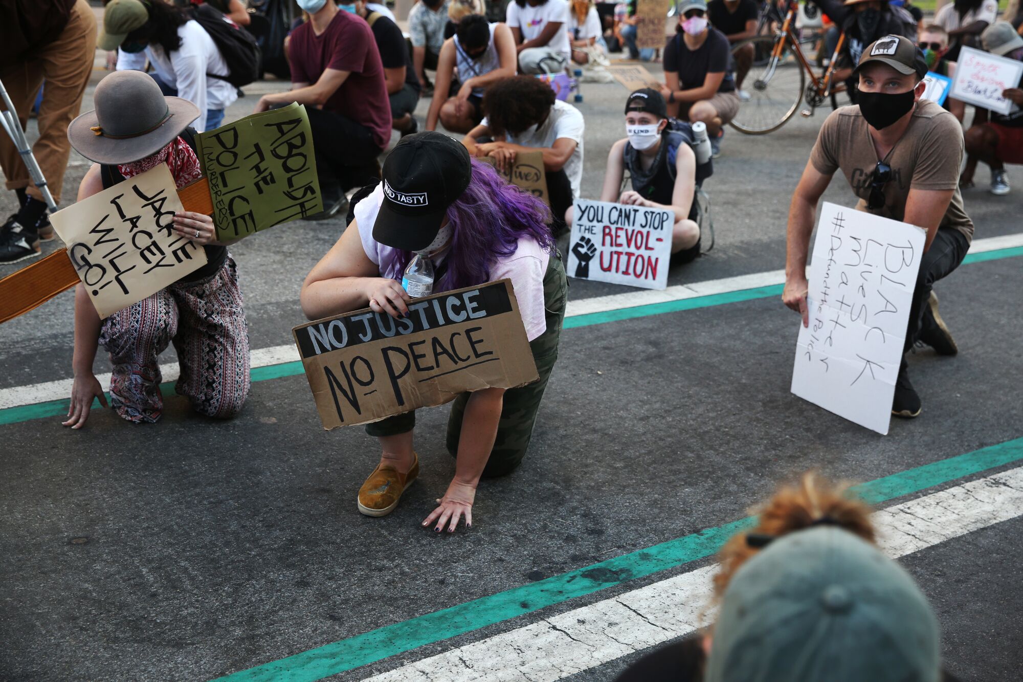 People take a knee to touch the ground during a Black Lives Matter Los Angeles and Build Power gathering in downtown L.A.