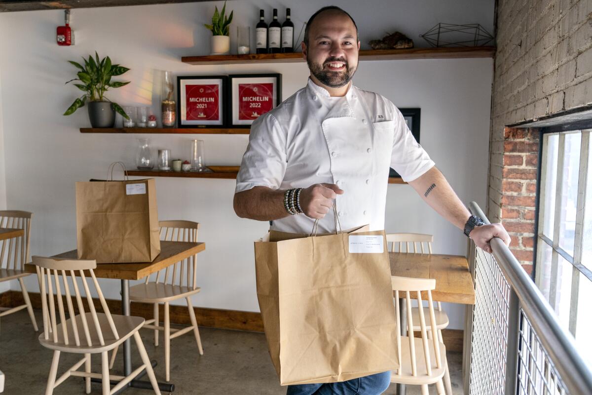 A man holding a paper to-go bag in a restaurant