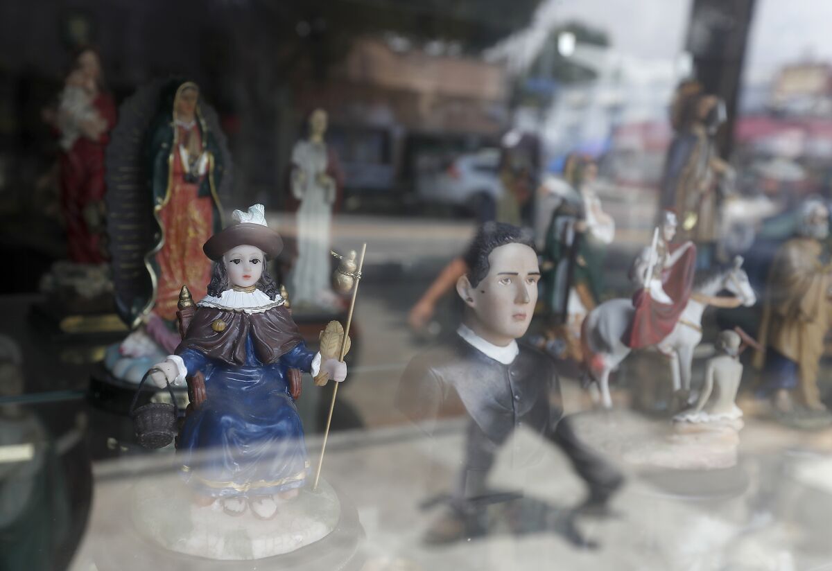 A figurine of Santo Niño de Atocha, left, shown in a display window of a botánica on Cesar Chavez Boulevard in Boyle Heights.