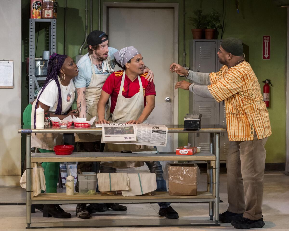 People dressed as workers at a diner interact on a stage.
