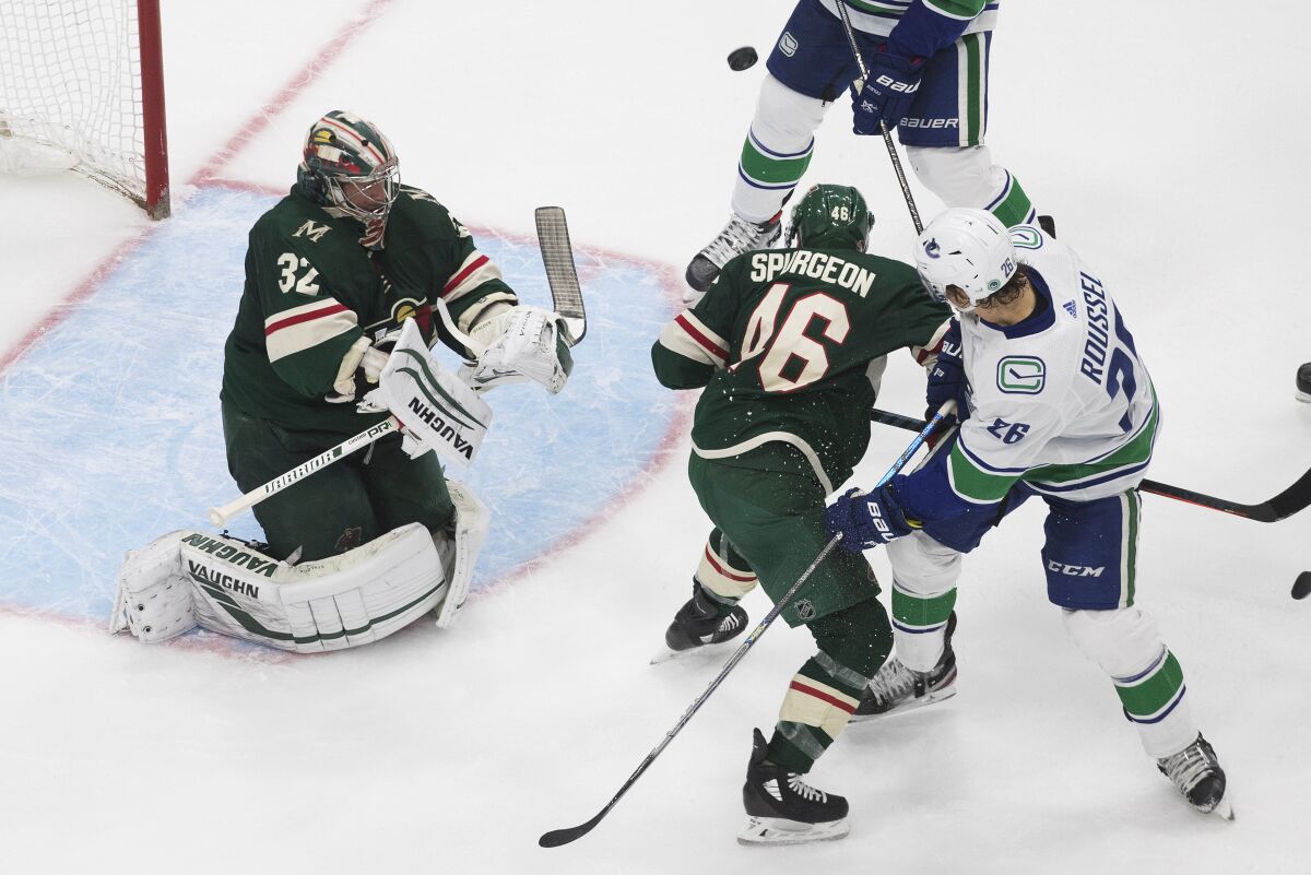 Minnesota Wild goalie Alex Stalock (32) makes the save as Jared Spurgeon (46) and Vancouver Canucks' Antoine Roussel (26) battle in front during the second period of an NHL hockey qualifying round game, Friday, Aug. 7, 2020, in Edmonton, Alberta. (Jason Franson/The Canadian Press via AP)