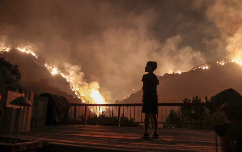 An 8-year-old child looks a flames near his backyard in Monrovia as the Bobcat Fire burns on Sept. 15, 2020. 