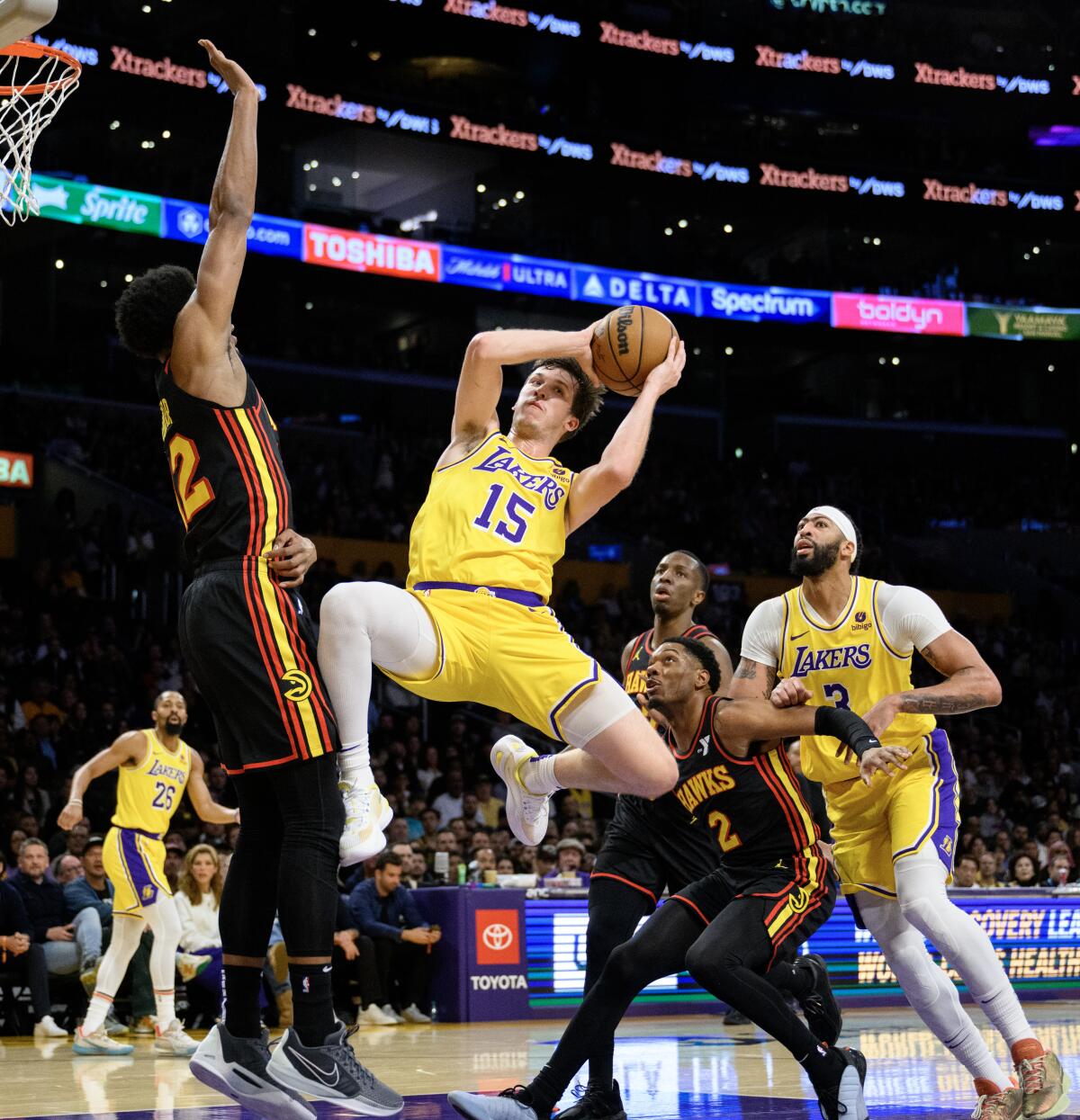 Lakers guardı Austin Reaves, Atlanta Hawks forveti De'Andre Hunter'ın önünde havada pas yapıyor.