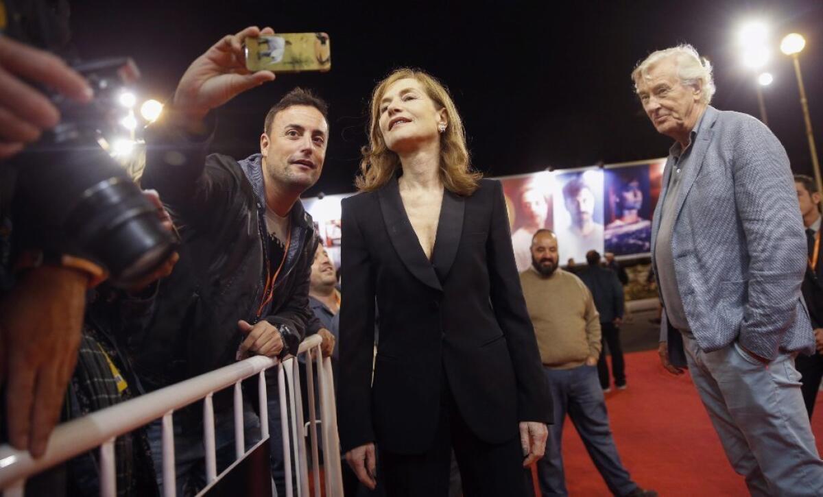 Isabelle Huppert poses for a festival selfie as director Paul Verhoeven looks on.