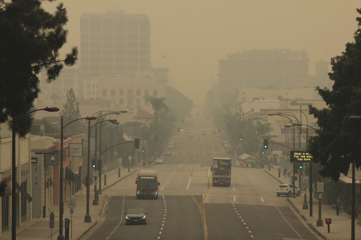 FILE - Smoke from wildfires fills the sky over Pasadena, Calif., in this view looking east down Colorado Boulevard in a Saturday, Sept. 12, 2020 file photo. The fires consuming the forests of California and Oregon and darkening the skies over San Francisco and Portland are also damaging an economy already struggling with the coronavirus outbreak. In the communities where they are raging, wildfires are destroying property, running up huge losses for property insurers and putting a strain on economic activity that could linger for a year or more. (AP Photo/John Antczak, File)
