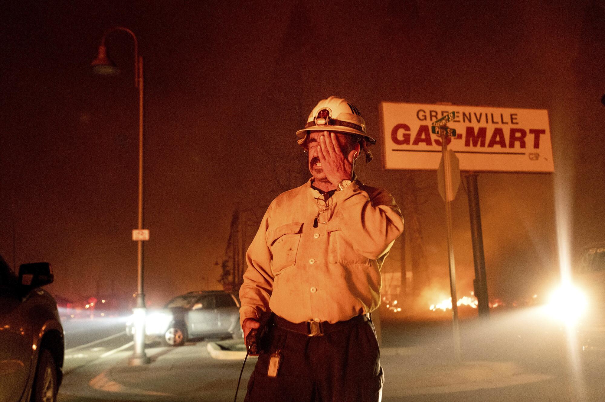 Battalion Chief Sergio Mora rubs his face as the Dixie fire tears through Greenville, Calif.