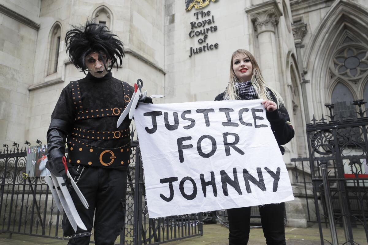 A man dressed as Edward Scissorhands and a woman hold a sign reading "Justice for Johnny"