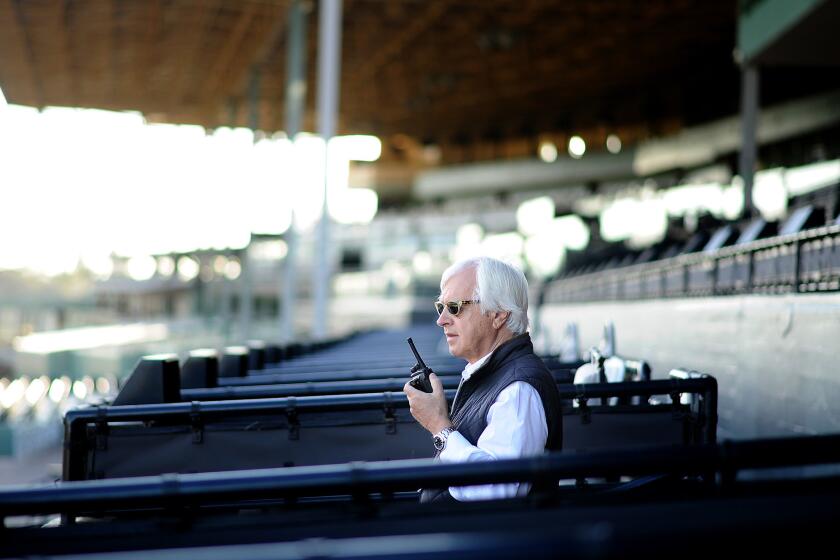 Hall of Fame horse trainer Bob Baffert keeps an eye on his horses during early morning workouts at Santa Anita racetrack.