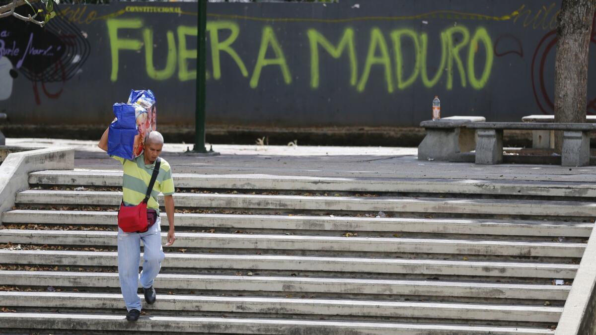 A man walks past graffiti that reads in Spanish "Get out Maduro" in Caracas, Venezuela on Jan. 24.