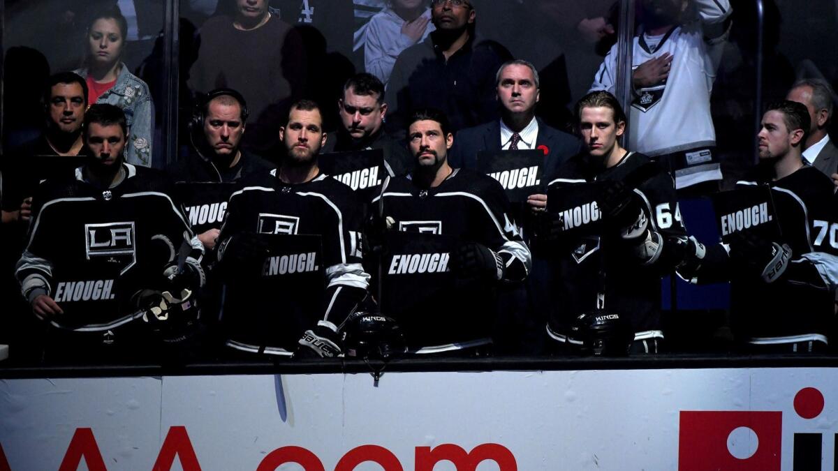 The Kings hold up signs with the word "ENOUGH" in reaction to the shootings in Thousand Oaks before the game against the Minnesota Wild at Staples Center on Thursday.