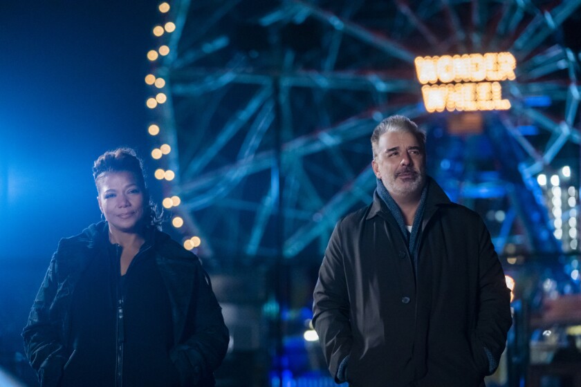 A woman and a man stand in front of a lighted Ferris wheel at night.