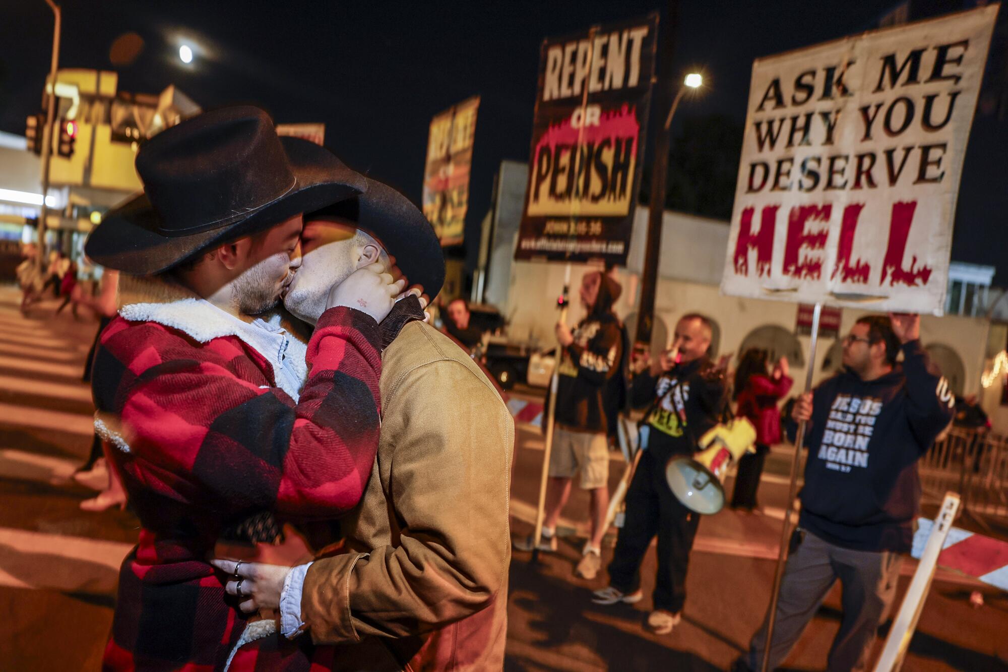 Cowboys engage in a long kiss in front of religious protesters near the entrance of the West Hollywood Halloween Carnaval. 
