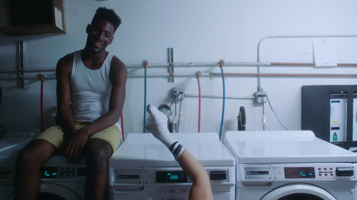 A young man sits on a washing machine.