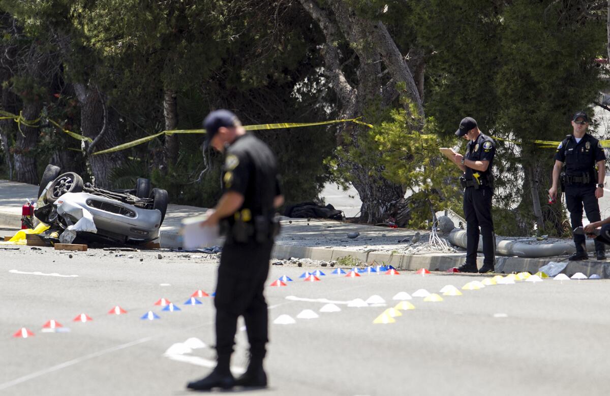 Newport Beach police officers survey the scene of a fatal car crash on Jamboree Road on Monday.