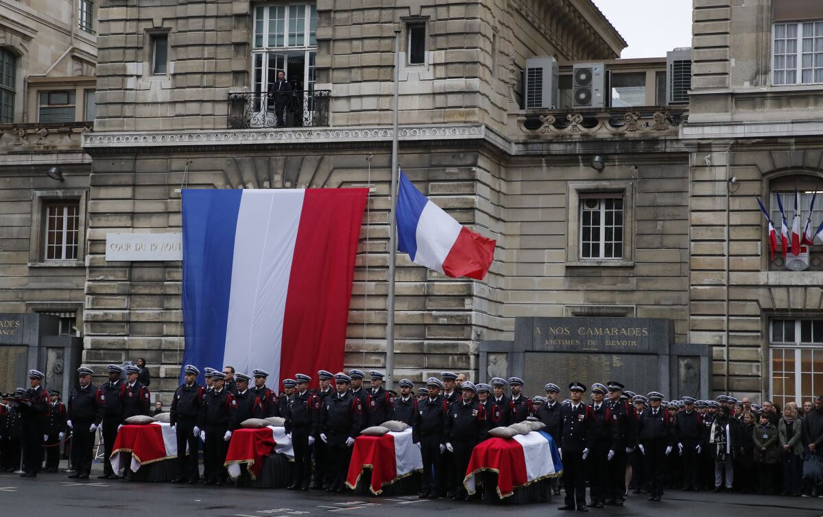 Police officers stand by the coffins of the four victims of last week's knife attack during a ceremony Oct. 8 in the courtyard of the Paris police headquarters.
