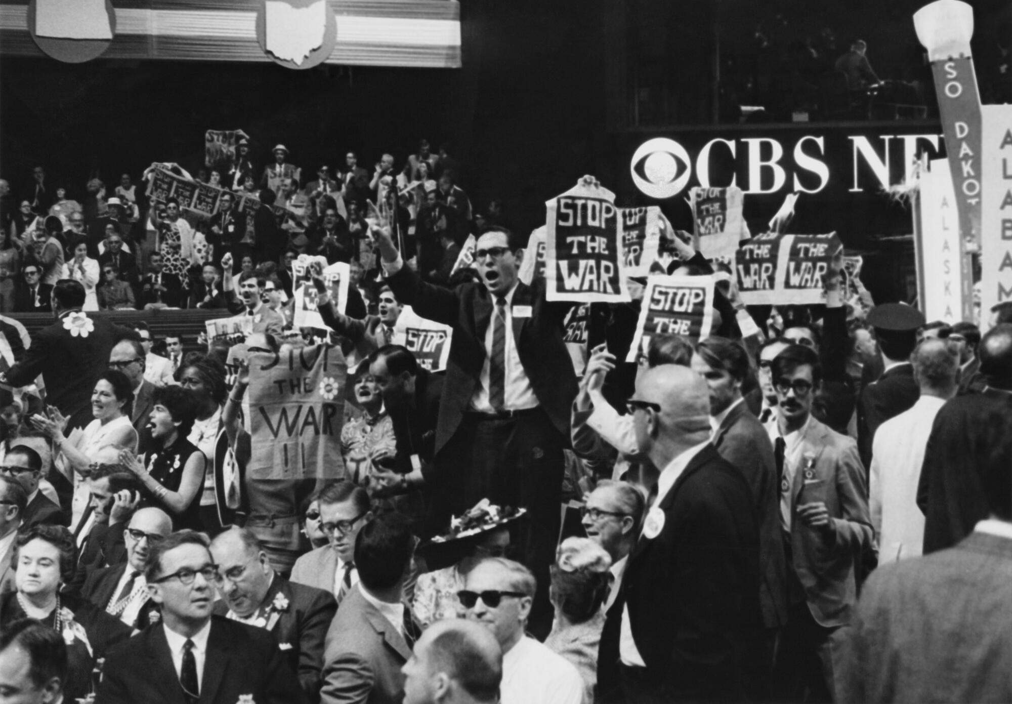 Delegates on the convention floor in 1968 hold signs that say 'Stop the War"