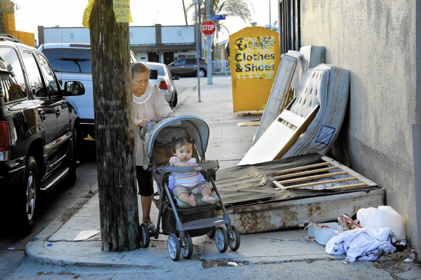 Anabel Rodriguez, 55, wheels her granddaughter Petra Rojas, 1, past discarded mattresses near a Planet Aid donation box on Lanfranco Street in East L.A.
