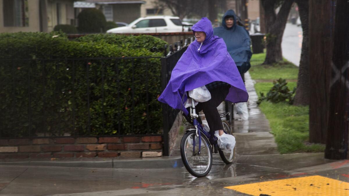 Residents try to stay dry wearing rain slickers and baggies on their shoes while bicycling in Alhambra during a February storm.