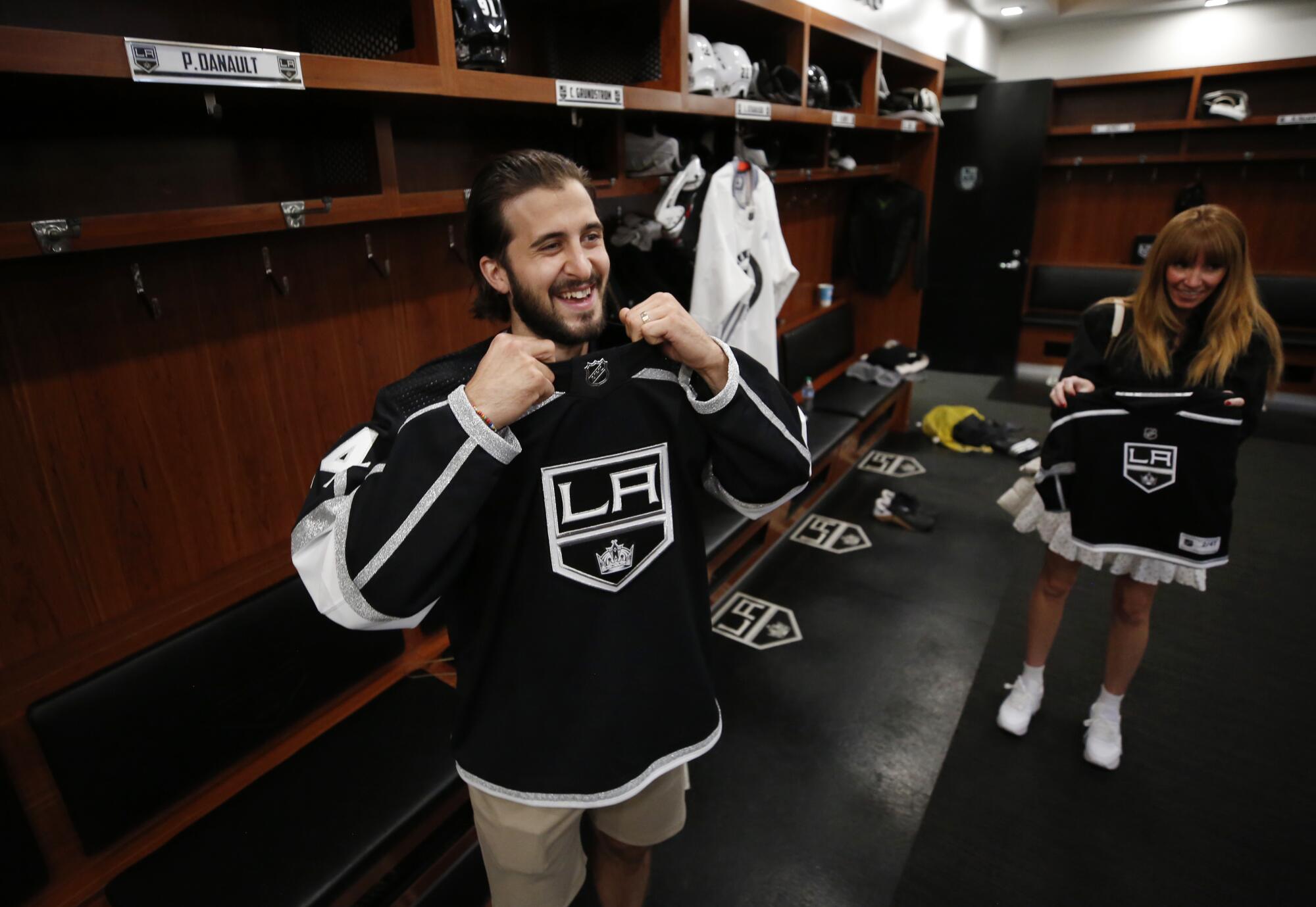 New Kings player Phillip Danault tries on his team jersey during a tour of the locker room. At right is his wife, Marie.