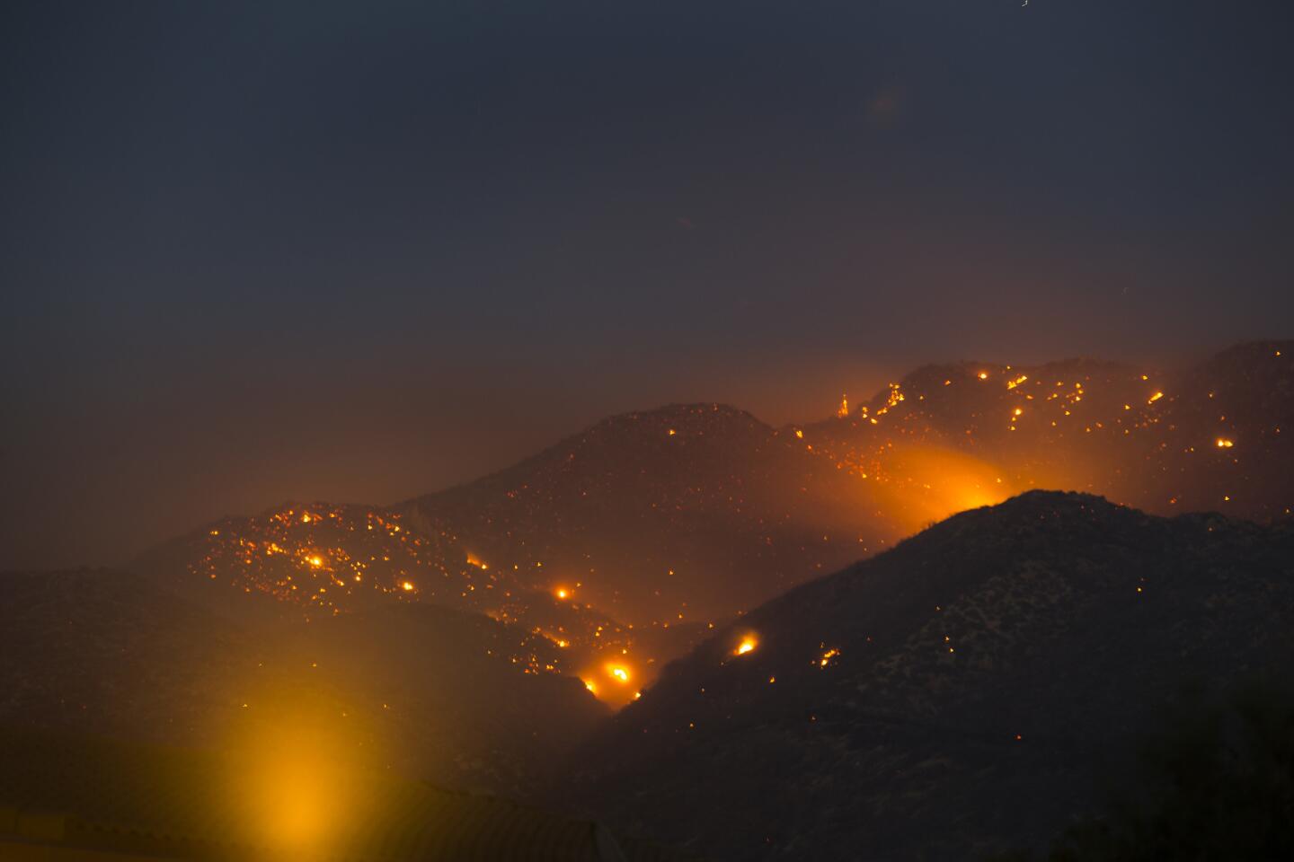 A long camera exposure captures the burning embers of the Pilot fire in mountainous terrain southeast of Hesperia in Summit Valley.