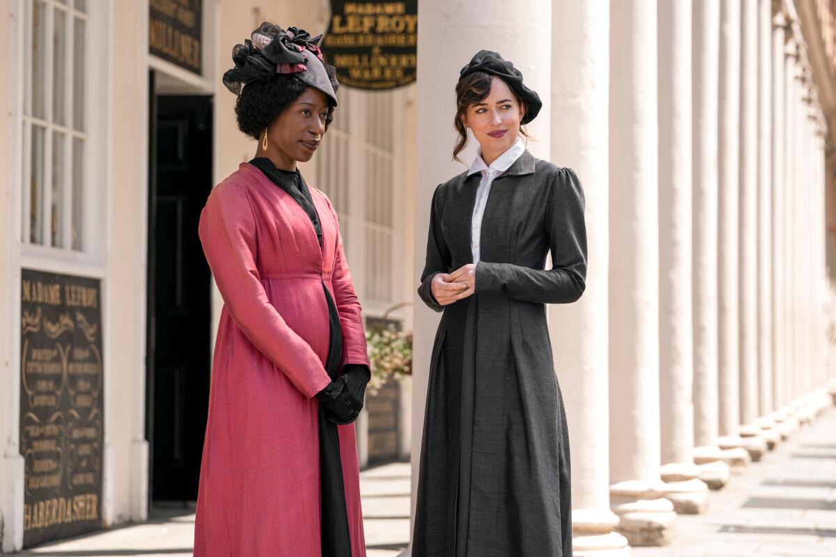 Two women in Regency-era attire stand in front of a shop.