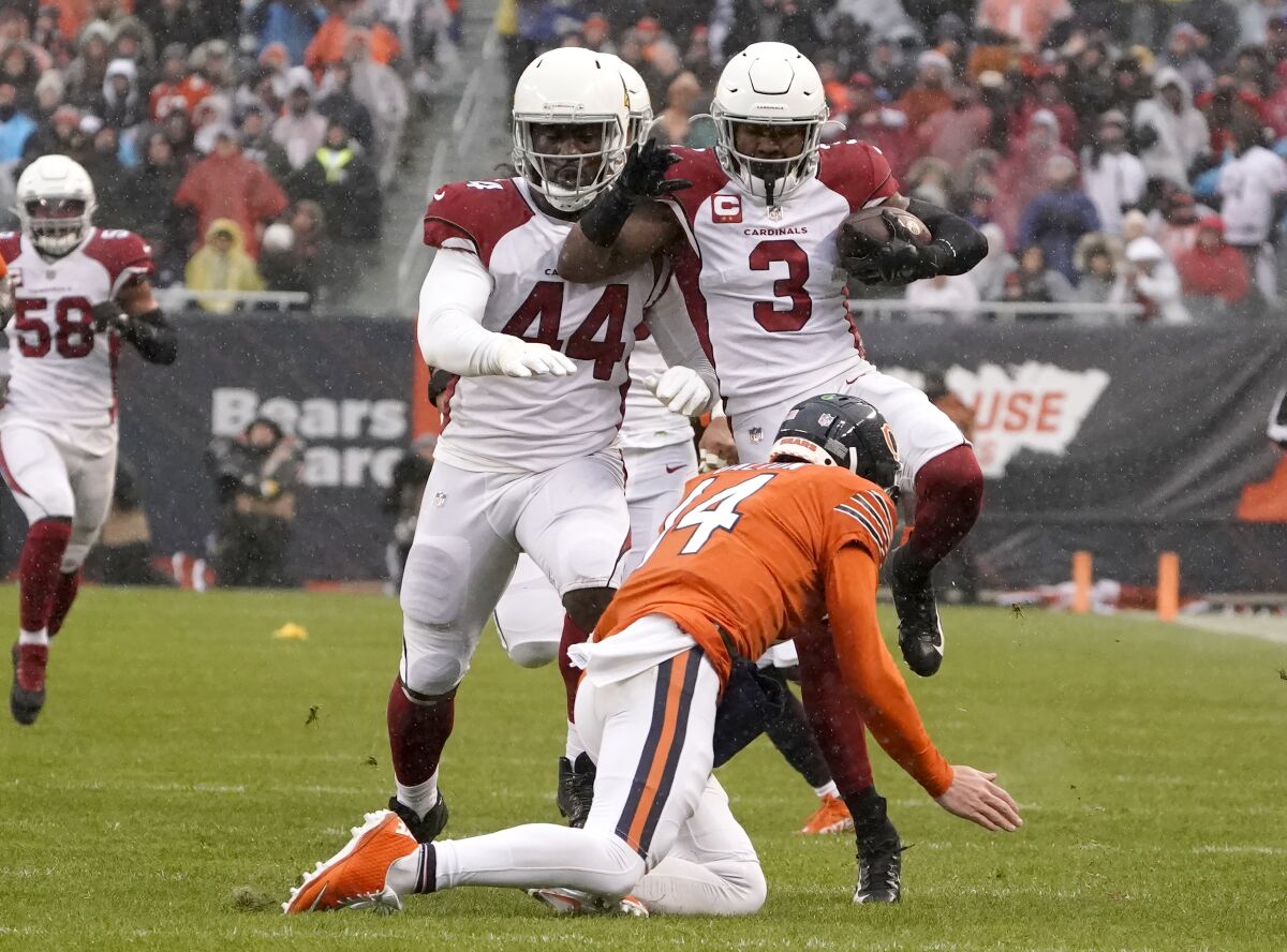 Arizona Cardinals safety Budda Baker (3) leaps over Chicago Bears quarterback Andy Dalton after Baker intercepted a Dalton pass during the first half of an NFL football game Sunday, Dec. 5, 2021, in Chicago. Running with Baker is Markus Golden. (AP Photo/David Banks)